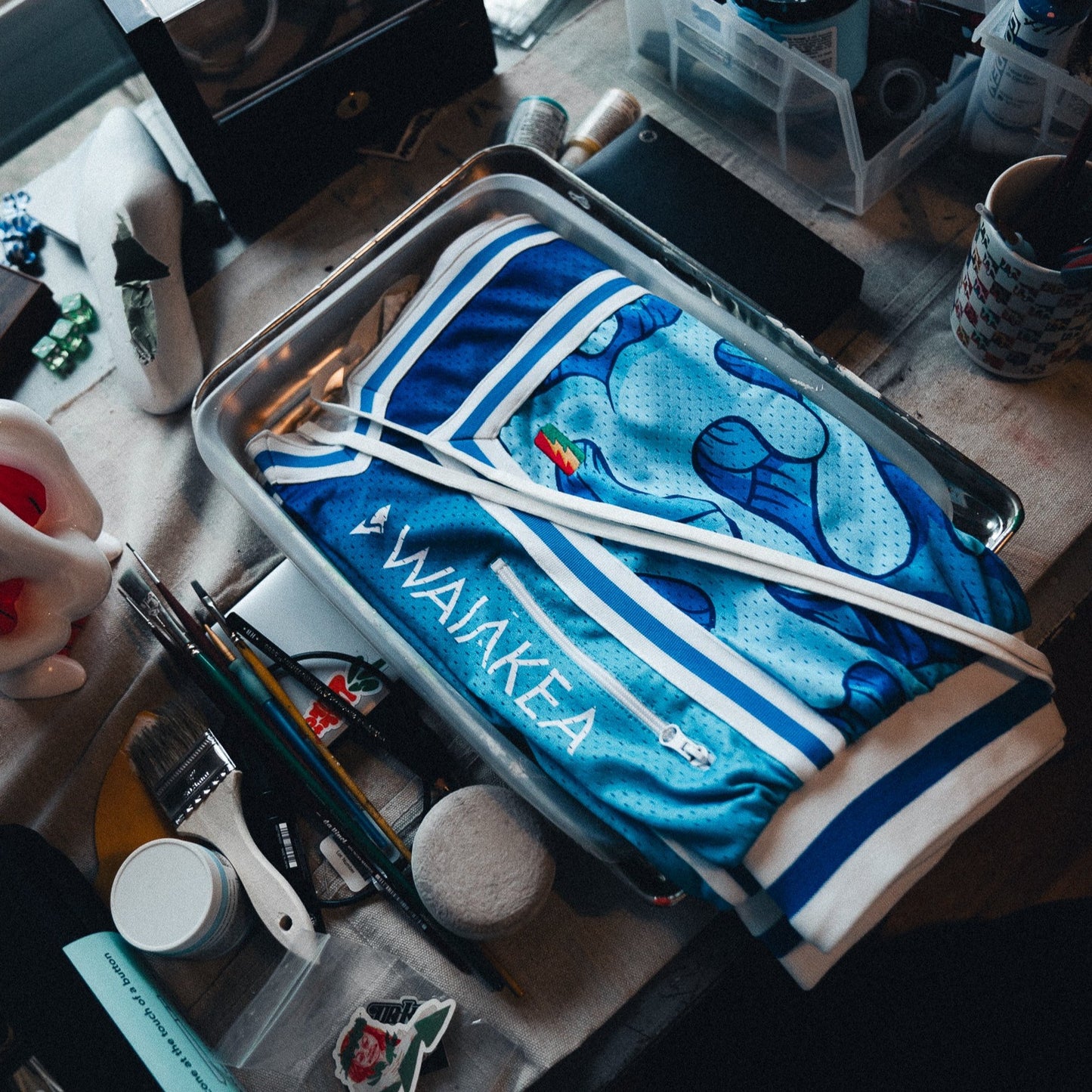 blue basketball jersey with waialkea logo on cluttered workspace table