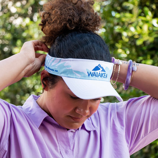 Person adjusting Waiakea visor outdoors.