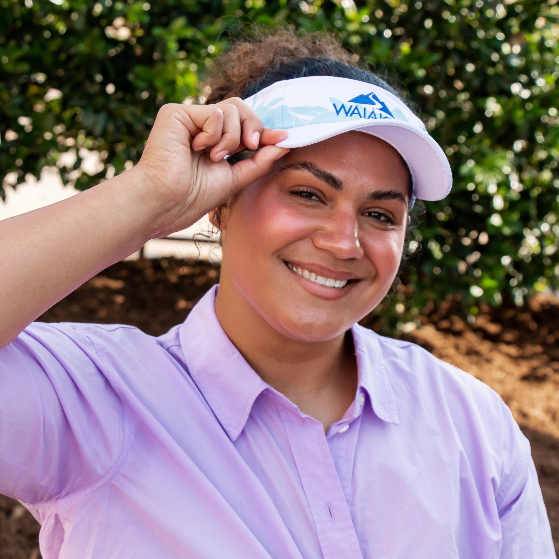Smiling person wearing white visor outdoors