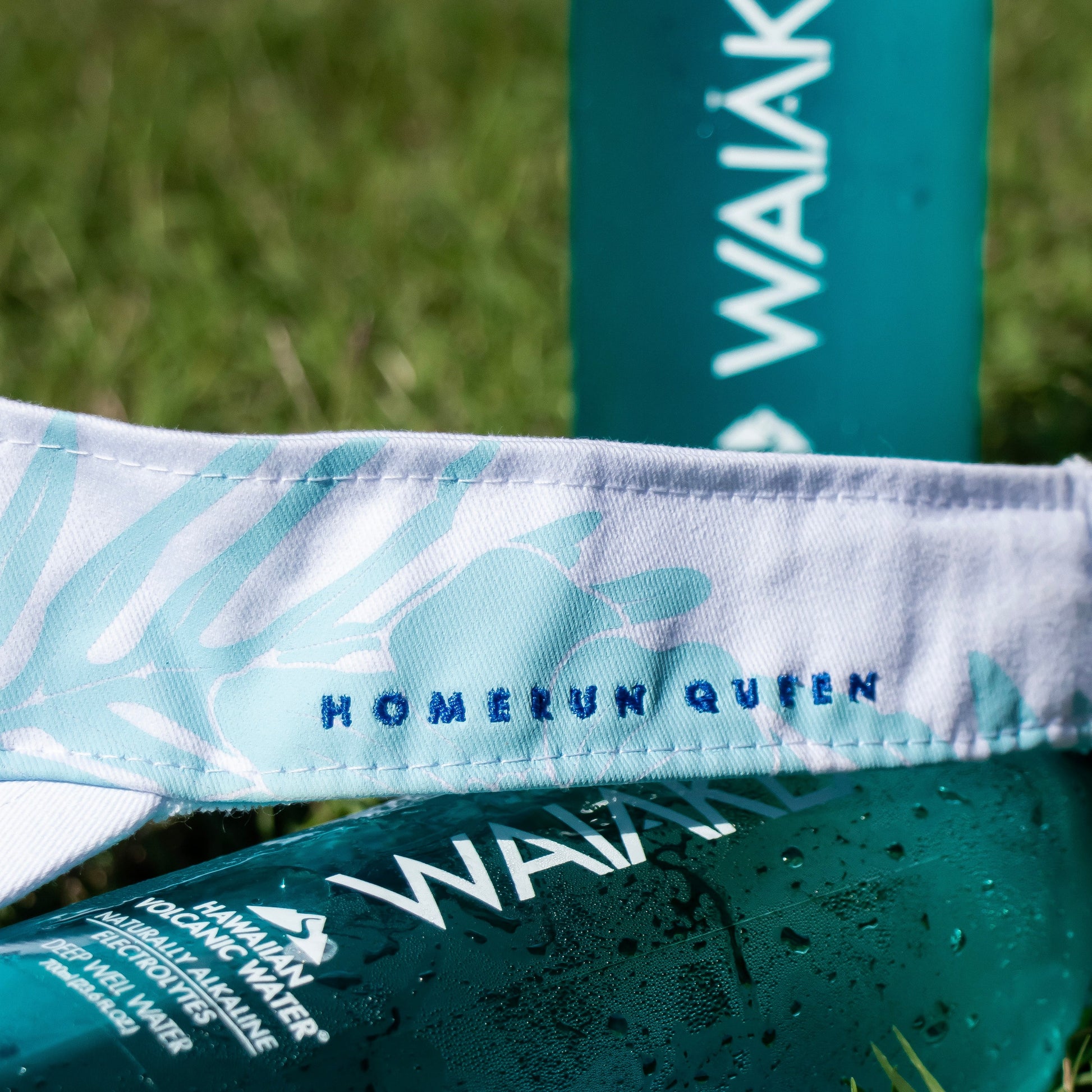 visor with HOMERUN QUEEN text next to Waiakea water bottle
