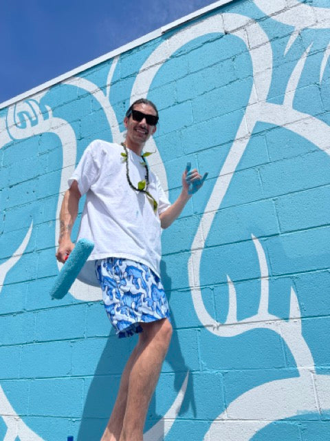 Man painting mural on wall with roller in sunny weather.