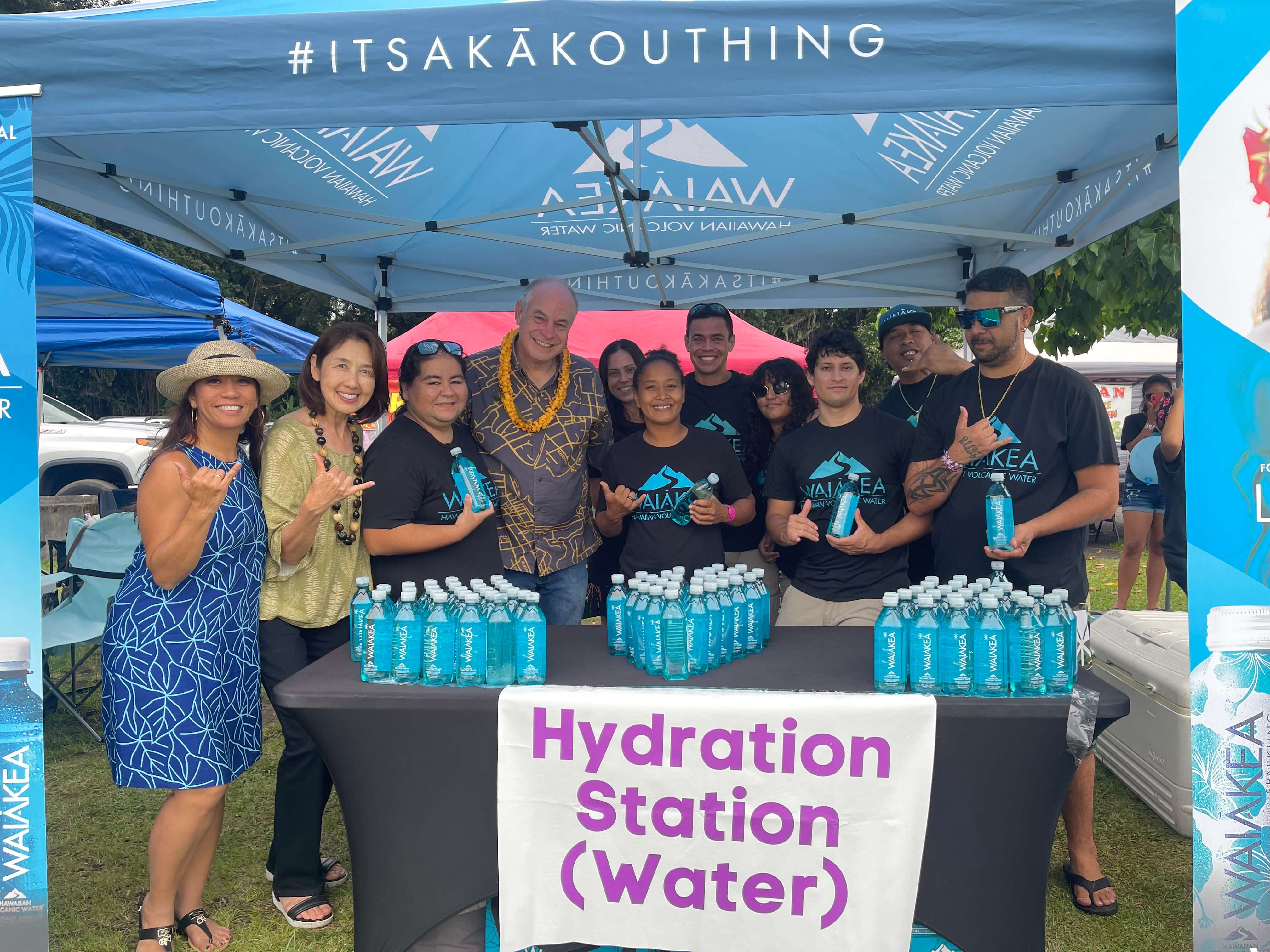 Group at Waiakea hydration station tent with bottled water display.