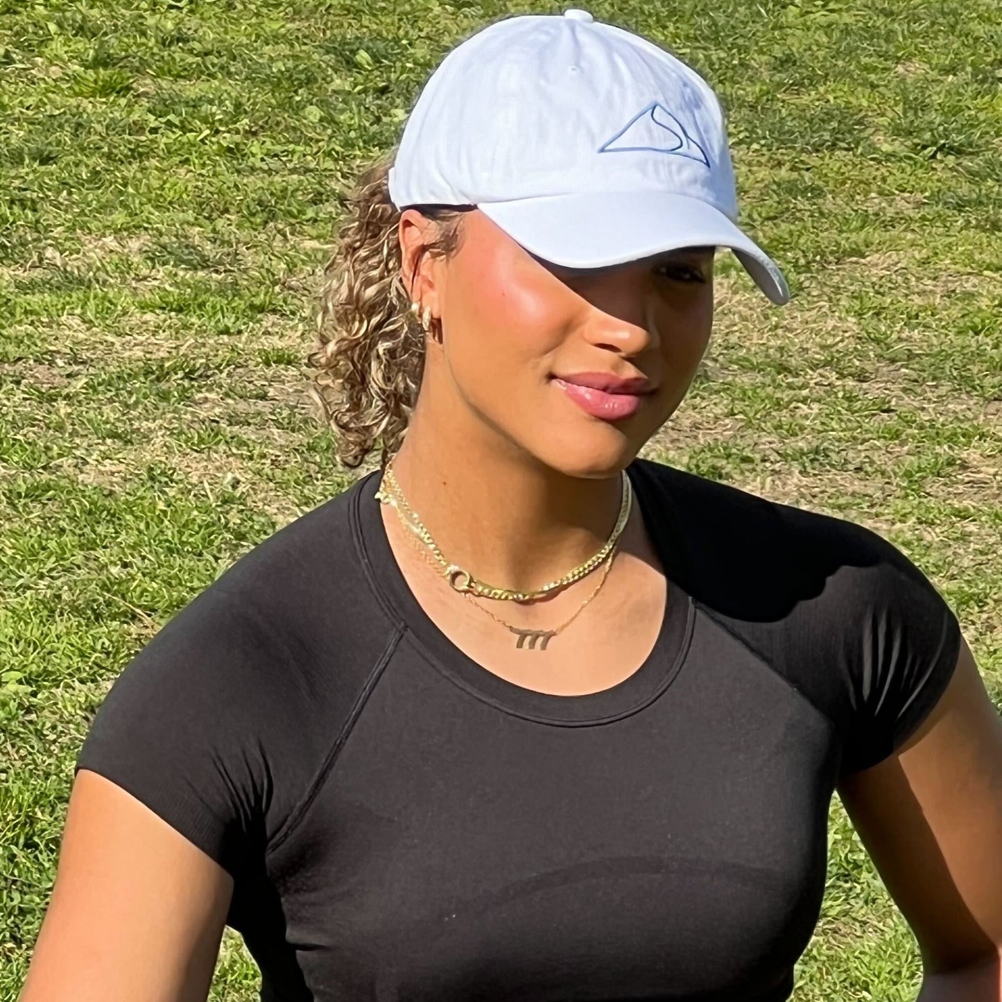 Woman wearing cap and black t-shirt outdoors