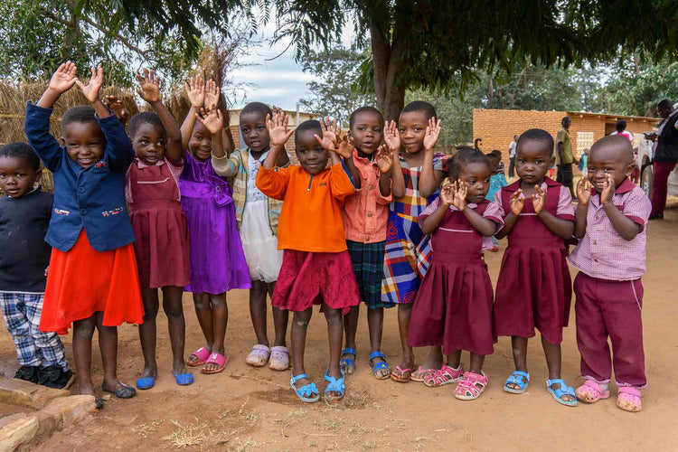 children raising hands in village setting