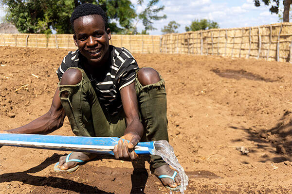 "young-man-irrigating-field-smiling"