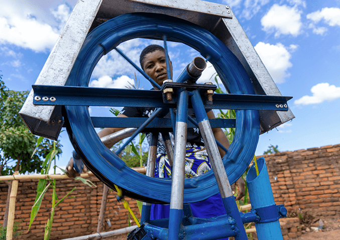 young person operating sustainable water pump in rural area