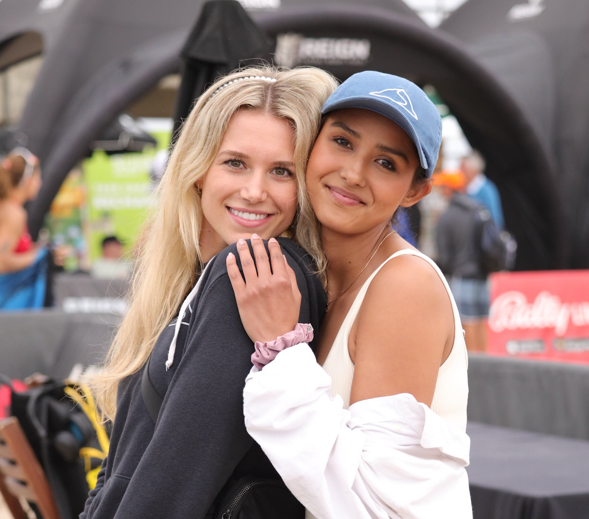 Two smiling friends hugging outdoors.