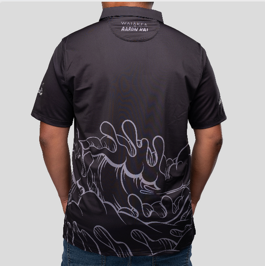 man wearing a black polo with an aaron kai wave on the front