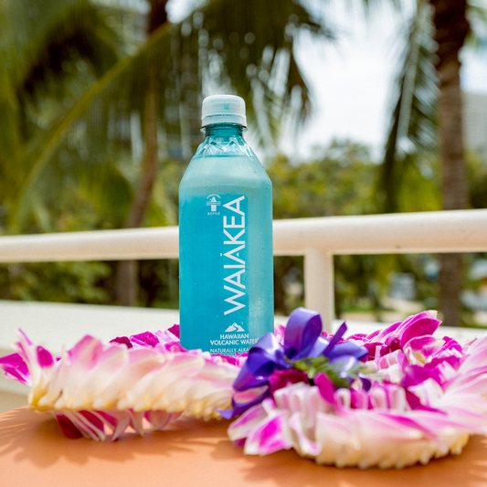 Waiakea bottle on a table with tropical flowers and blurred palm trees in the background
