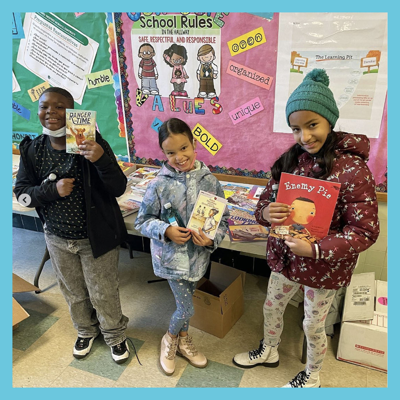 children holding books in classroom with school rules poster