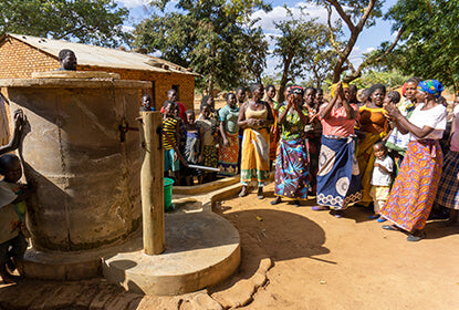 Community gathering around water well in rural village.