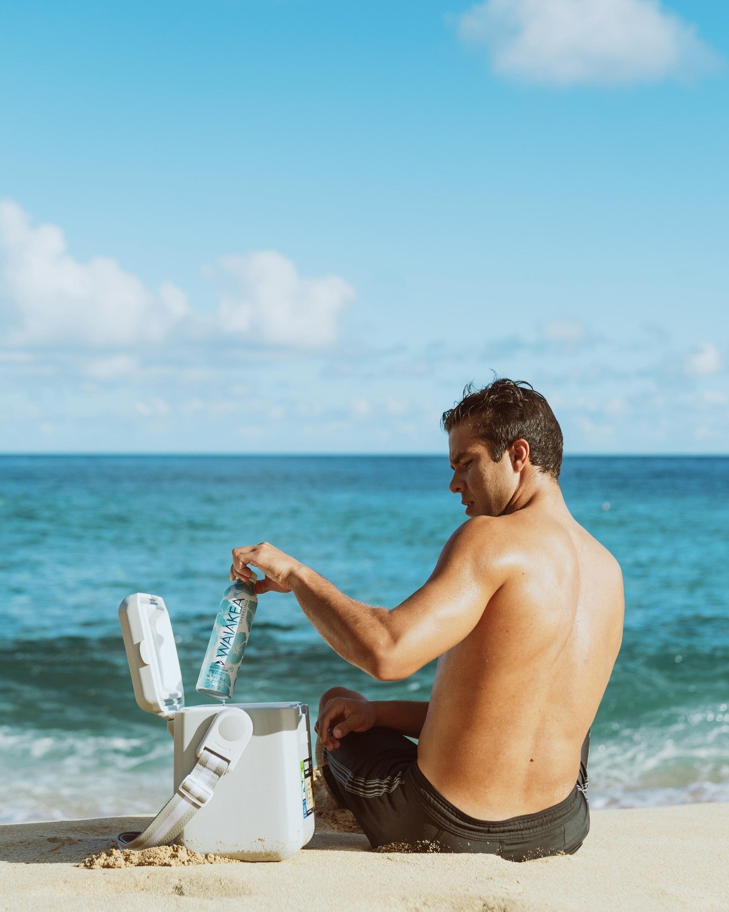 Man sitting on beach with cooler and bottled water