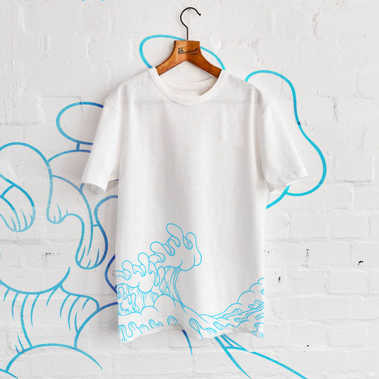 White t-shirt with blue wave design hanging on wall.