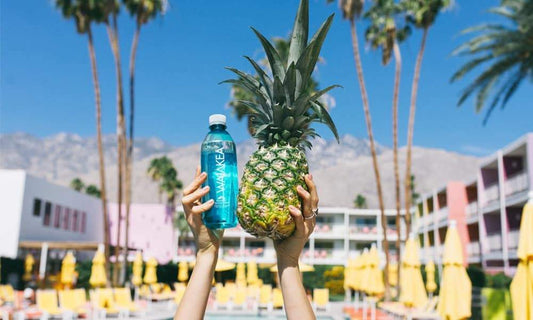 Person holding up a pineapple and Waiakea bottle