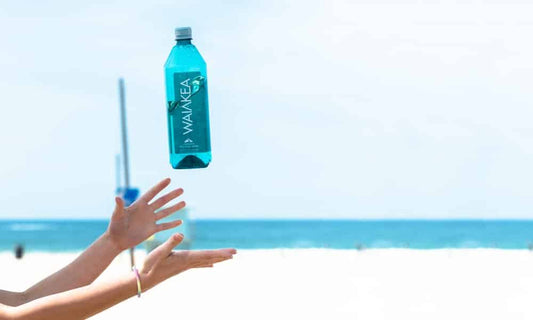 Person catching a Waiakea bottle on the beach