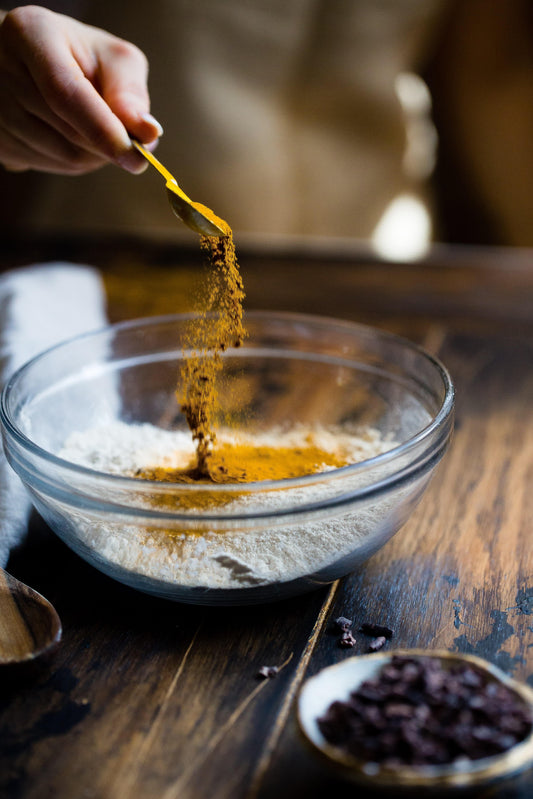 Hand pouring turmeric into a bowl