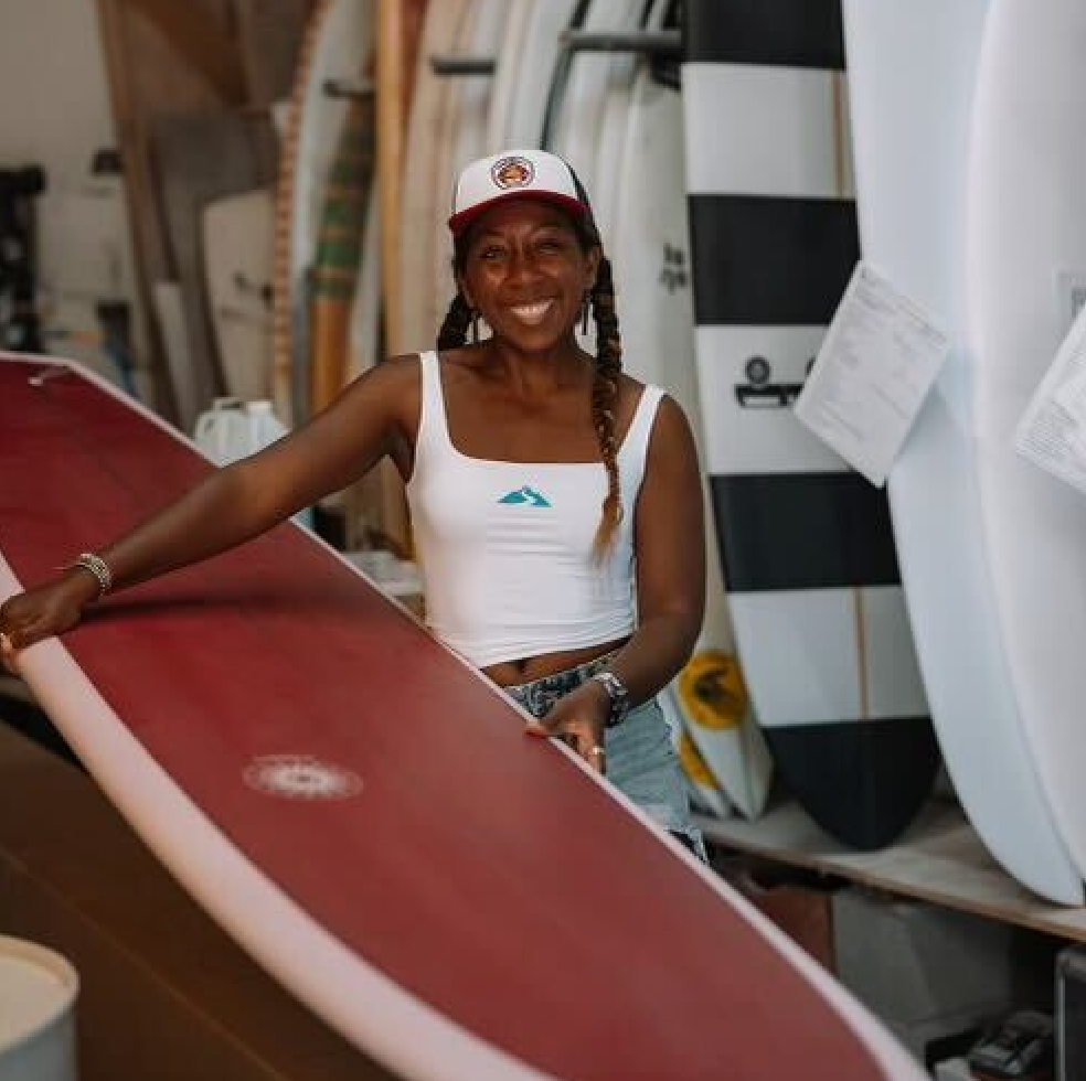 Woman holding red surfboard in surf shop