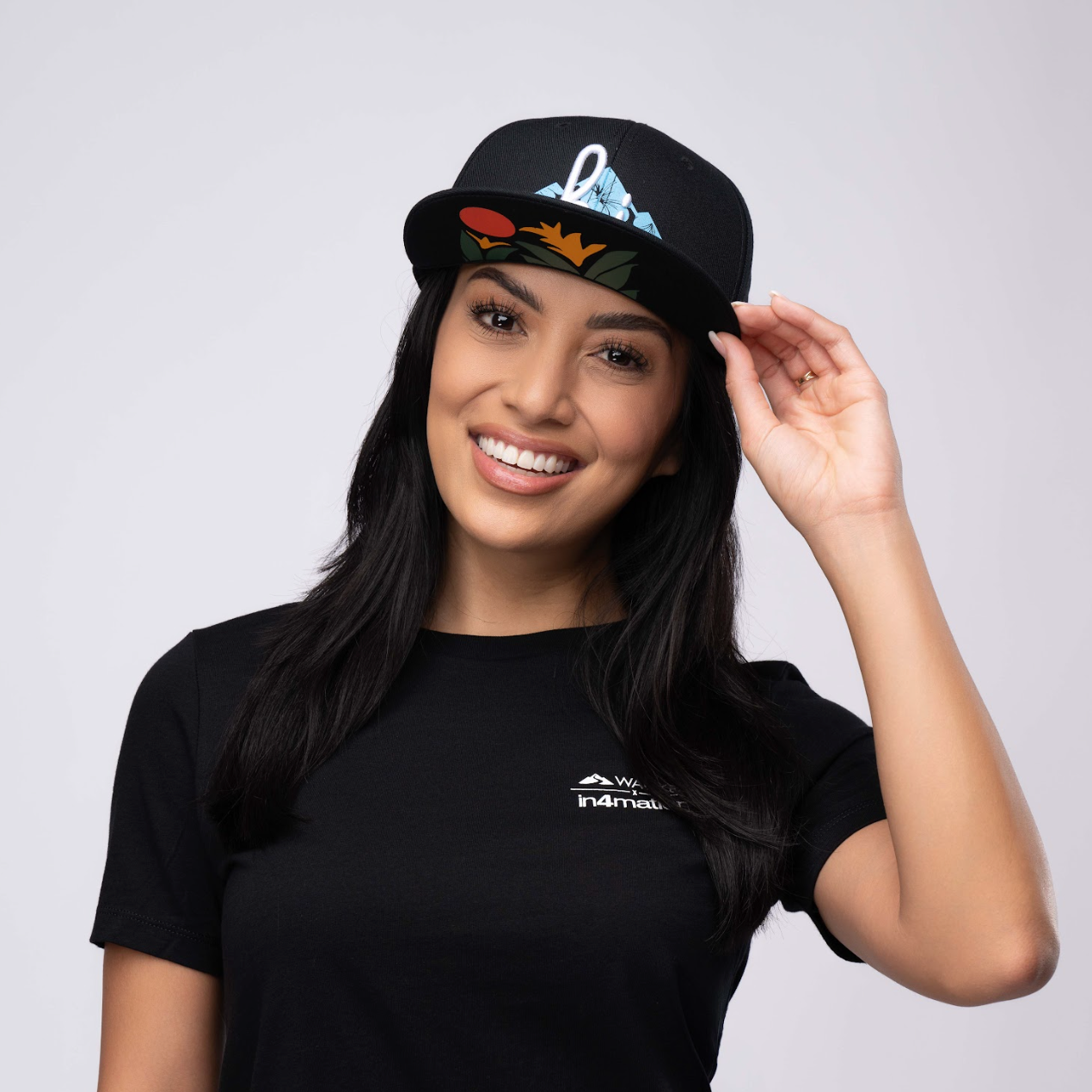 woman wearing a snapback hat with "hi" and volcano logo 