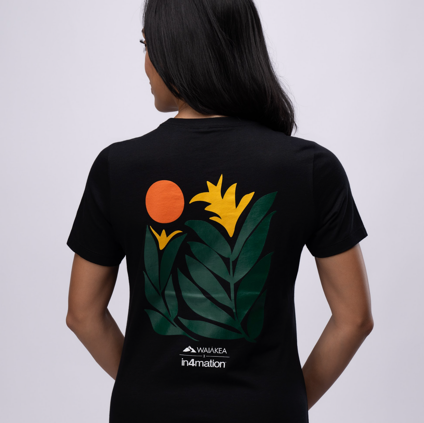 Back of black T-shirt with tropical graphic design featuring orange sun and yellow flowers.