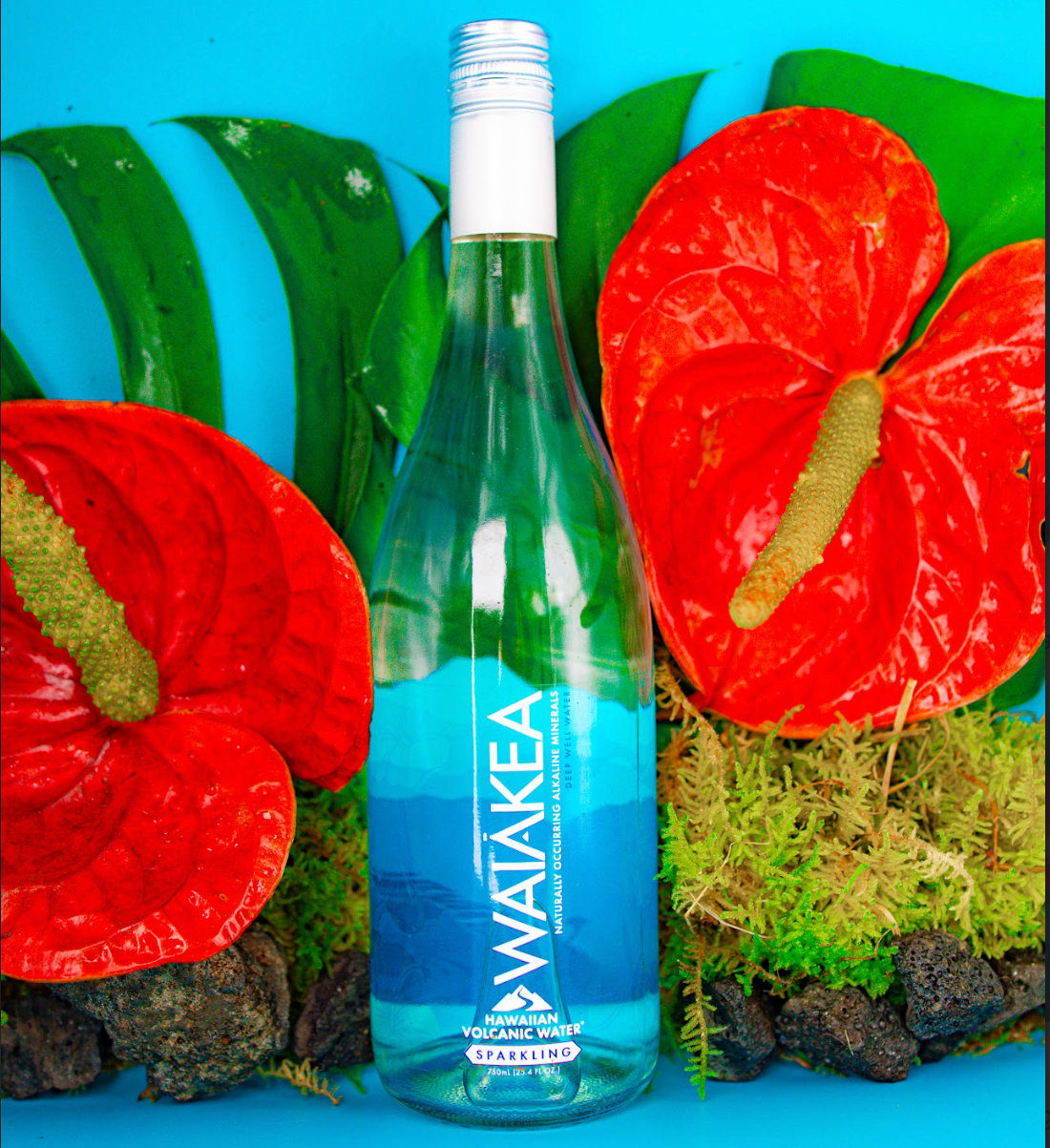 Clear bottle with blue label against a blue background with red flowers and green leaves