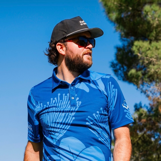 Man wearing blue patterned polo and cap outdoors.